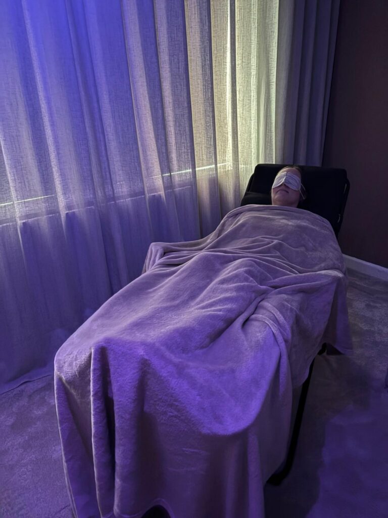 Client relaxing under a warm blanket with a self-heating eye mask during a reflexology treatment in Thelwall, Cheshire.